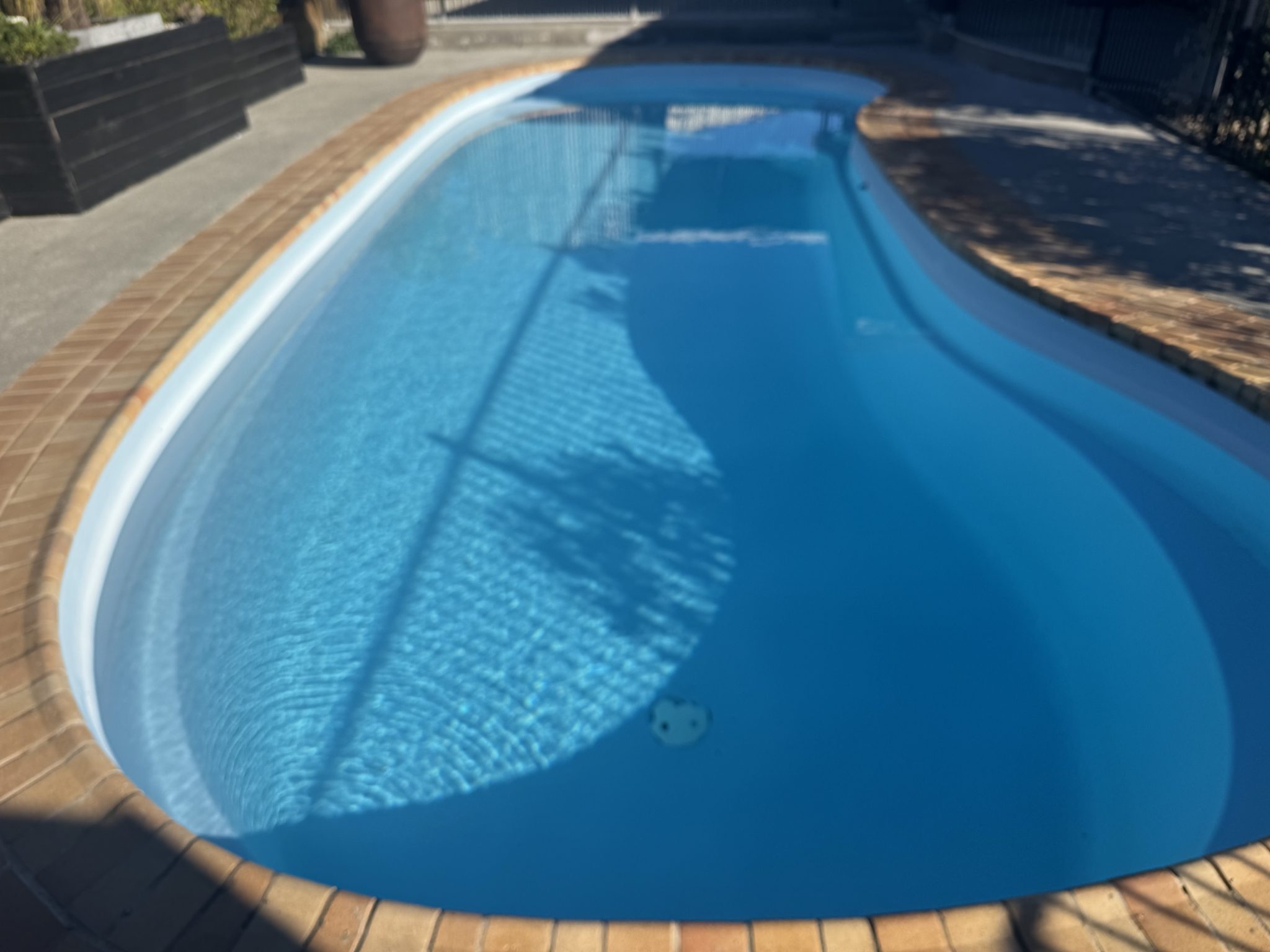 Kidney-shaped fibreglass pool refilled with clean blue water