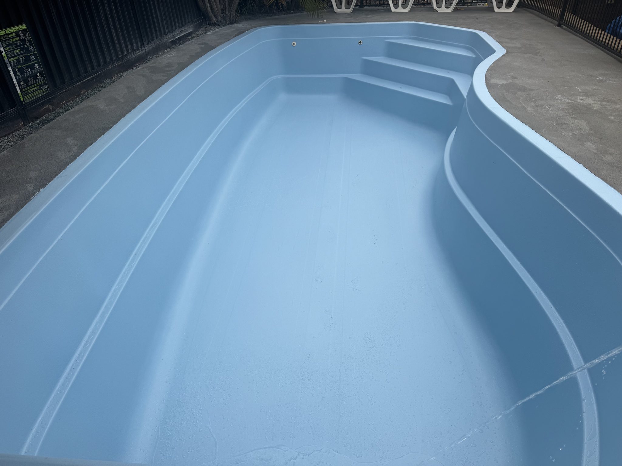 Resurfaced pool with new corner steps and a light blue finish