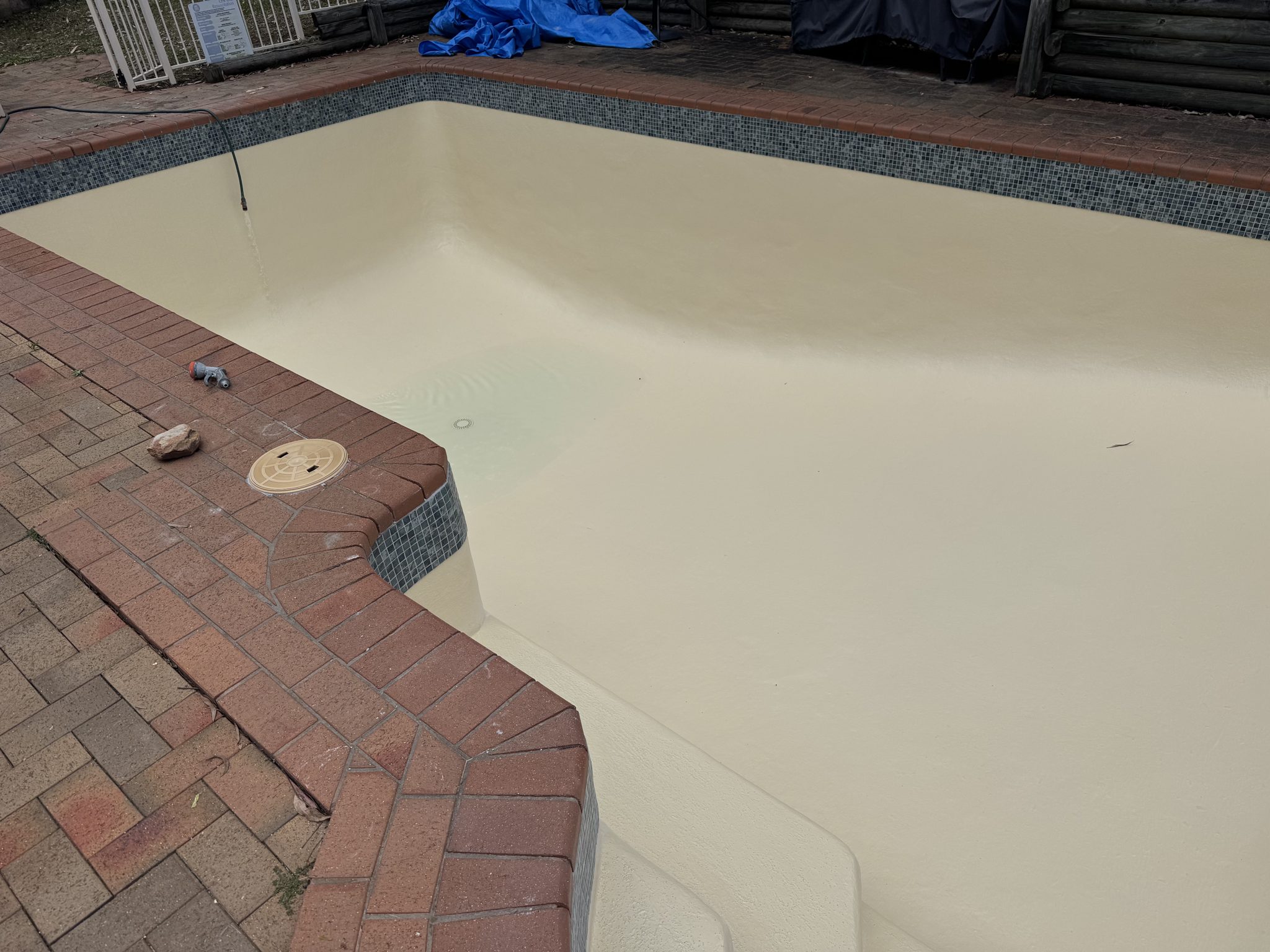 Pool finished in a warm cream fibreglass coat with mosaic waterline